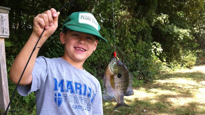 young boy holding up fish on line