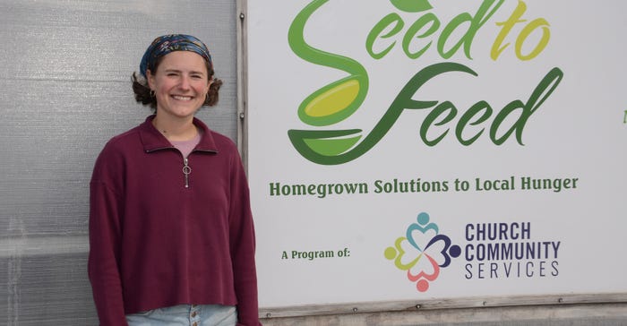 Gabby Parrish standing next to Seed to Feed sign in greenhouse