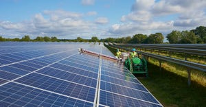 Workers use machinery to clean the solar panels on their farm