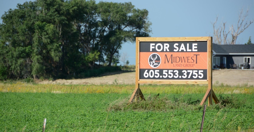 A for-sale sign on a plot of farmland
