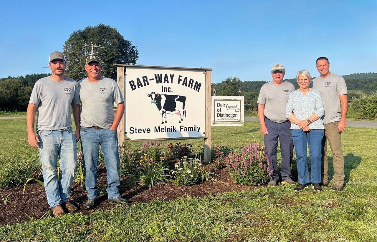 Multi generational family pose near a dairy farm sign