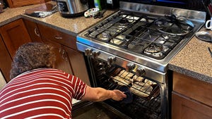 A woman putting sandwhich rolls in the oven