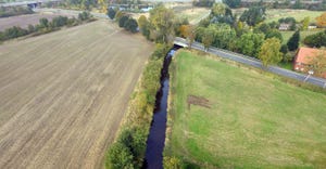 straight creek running between agriculture fields