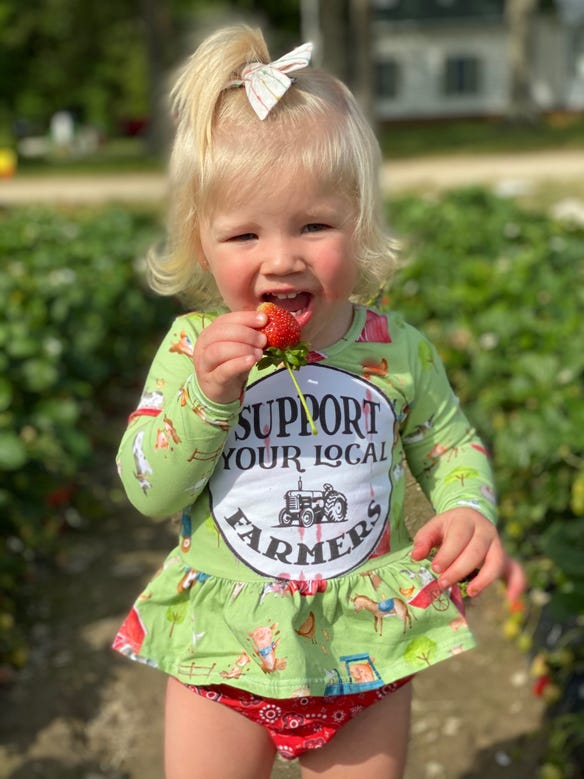 A young girl gorges on a strawberry