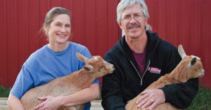 Mike Hoopengardner and Kristy Kikly holding goats in front of red barn