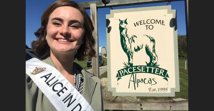 Alice in Dairyland Julia Nunes stands in front of Pacesetter Alpacas farm sign