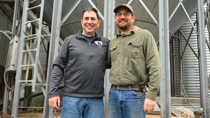 Bill and Matthew Beam standing in front of grain bins