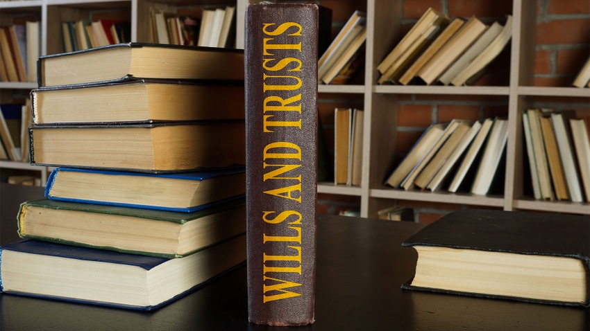 A book titled Wills and Trusts sits on a desk near a stack of other books