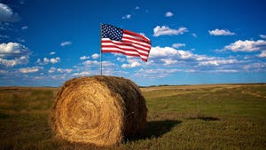 American flag on round hay bale in field
