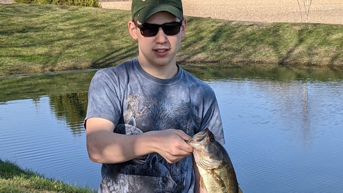 teenage boy holding fish he caught by the mouth teenage boy holding fish he caught by the mouth