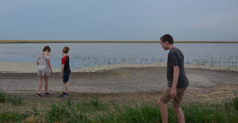 The grandkids are Geneva, left, Dylan and Lewis. exploring one of the several Playa Lakes that dot the farm