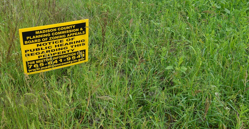 Notice of Public Hearing sign in tall grass