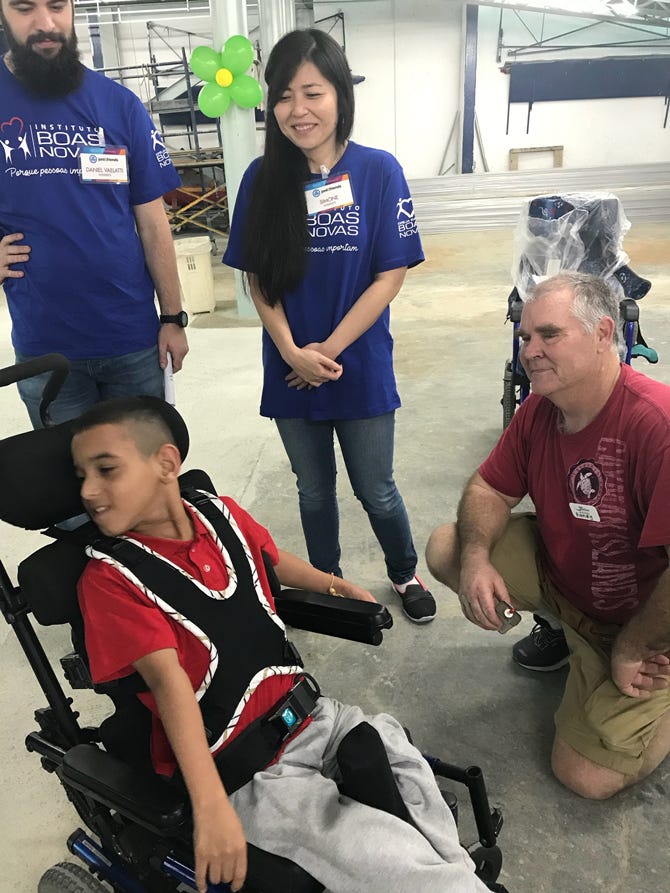 Randy Overman and two Brazilian teammates help Brazilian boy in wheelchair