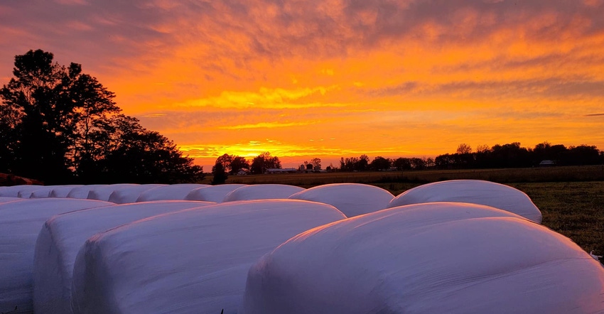 orange and purple sunset over round hay bales orange and purple sunset over round hay bales