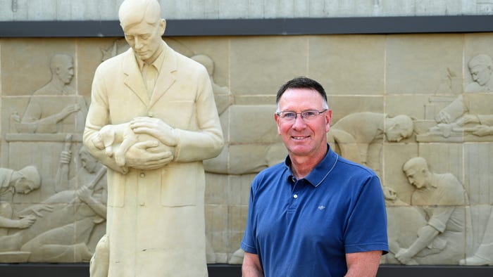 Man next to stature of veterinarian holding puppy Man next to stature of veterinarian holding puppy