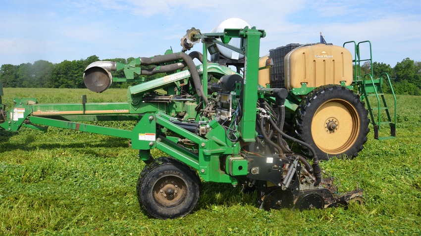 A corn planter planting seed into a green cover crop