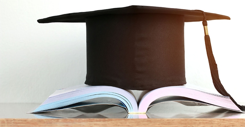Education or knowledge. Graduation hat on open textbook on wooden desk in library archive room, 