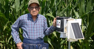 Dave Nanda inspects a WatchDog weather station at the edge of a cornfield