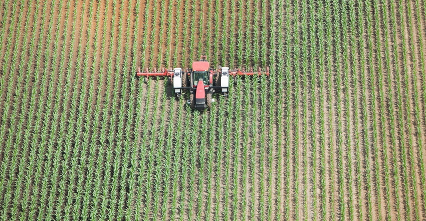 Aerial view of tractor applying liquid nitrogen fertilizer to corn field