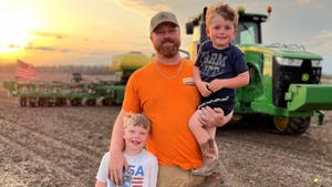 Mike Daniels standing in field at sunset with sons Lawson and Bronson
