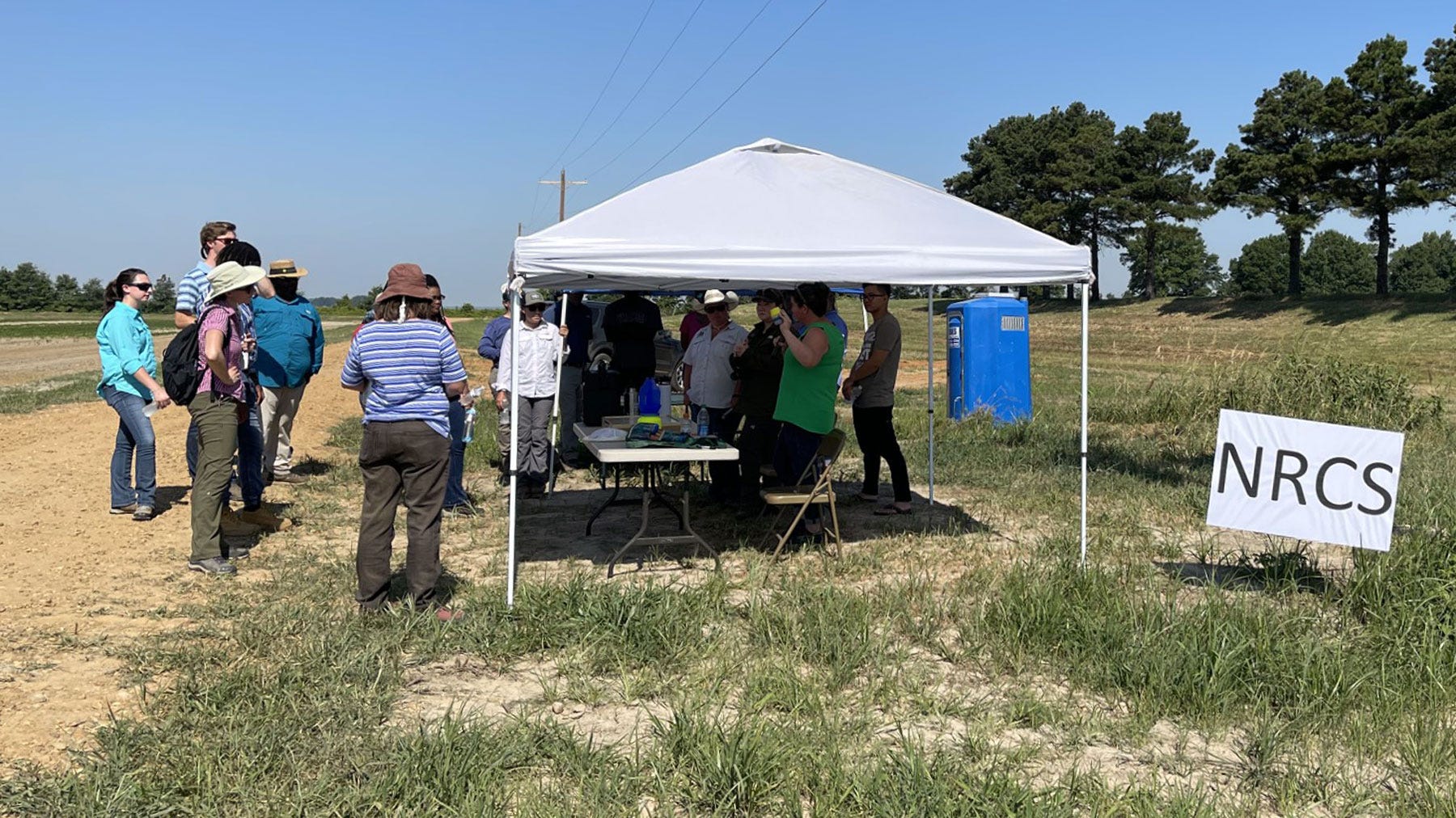 People meeting under a tent at a USDA NRCS field day.