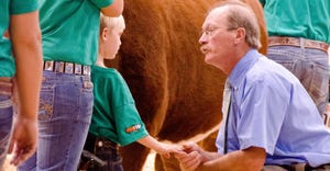 Jim Bloomberg kneeling and talking to a young Nolan Lee at a cattle show