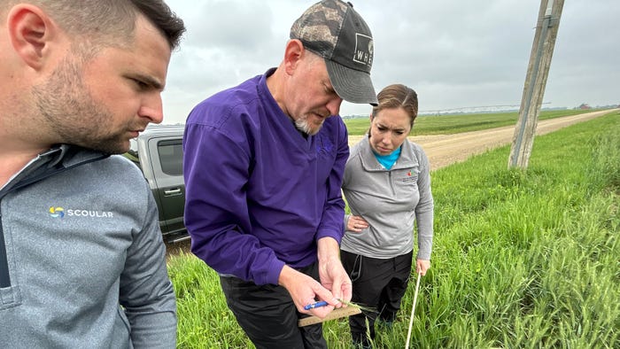 Kansas Wheat VP of Research Aaron Harries showing two attendees how to measure wheat