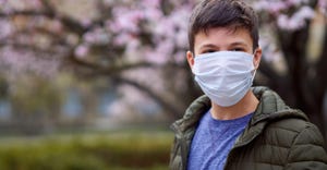 A teenage boy wearing a surgical face mask outdoors