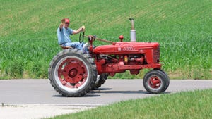 A tractor enthusiast waves during the Tractor Cruise