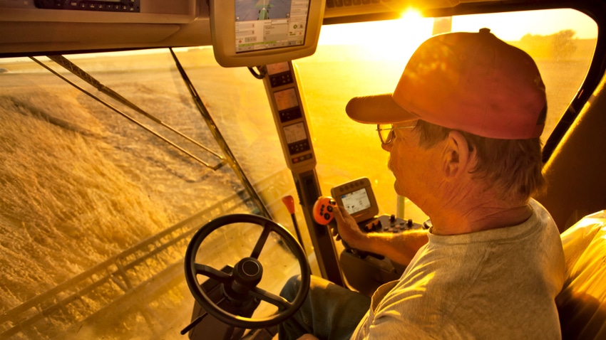 View of farmer from inside cab of a combine