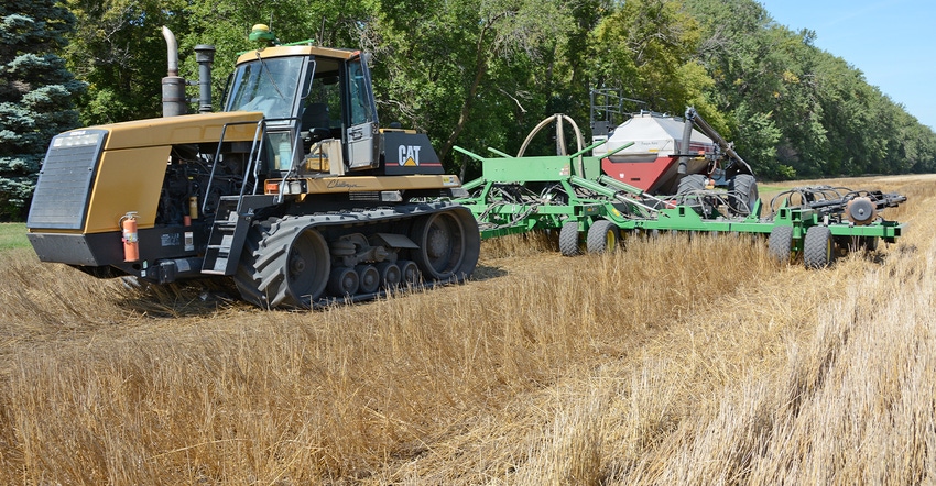 Caterpillar tractor pulling planter seeding soybean into wheat stubble