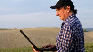 Man with a laptop standing in a field