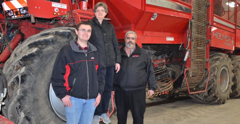 Dean and Donna Haubenstricker with their oldest son, Josh standing with a sugarbeet harvester