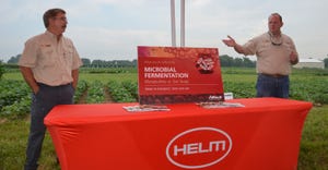 Brian Springer, left, of Alltech Crop Science and Adam Hensley of Helm stand at a table and speak at a field day