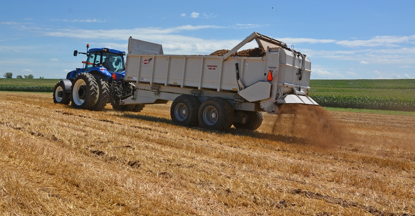 truck driving through field spreading manure