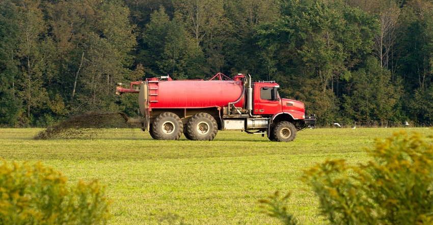 A red tractor spreading liquid manure in a field