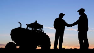 Silhouette of two farmers shaking hands next to tractor