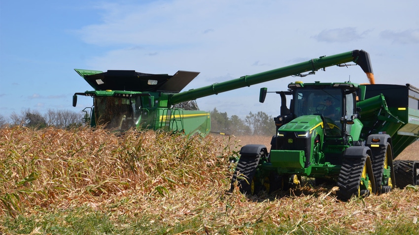 A combine and tractor harvesting a cornfield
