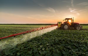 farmer spraying pesticides on field
