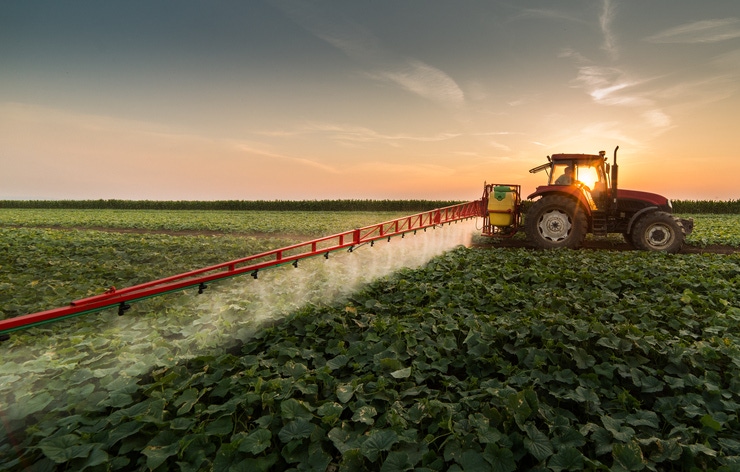 farmer spraying pesticides on field