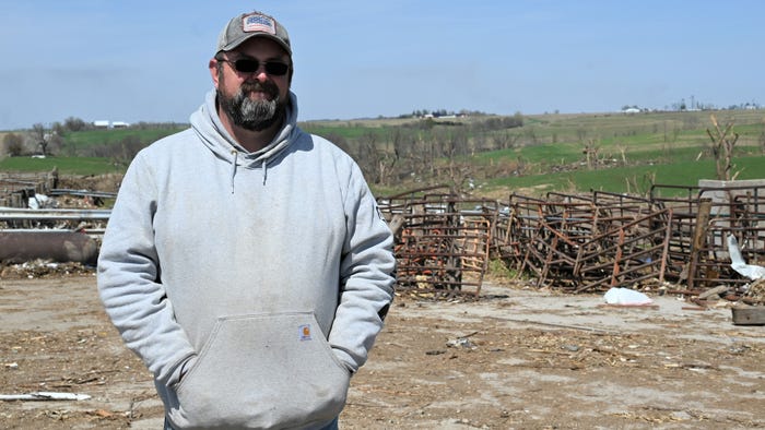 Wellman farmer Clint Whetstine stands in front of destroyed pens and barns from tornado.