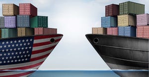Two container ships. One with American flag across ship and one unmarked.