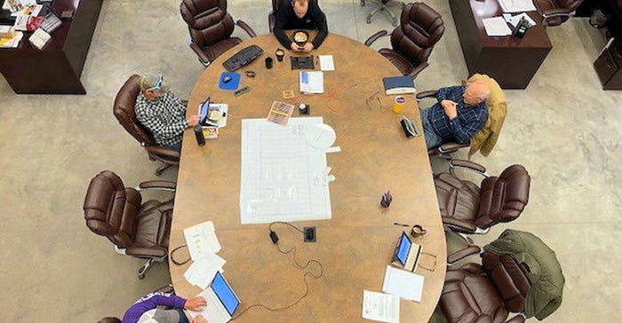 overhead view of four people spaced at a big conference table.