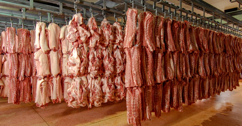Pork cuts hang in refrigerated storage at a slaughter house