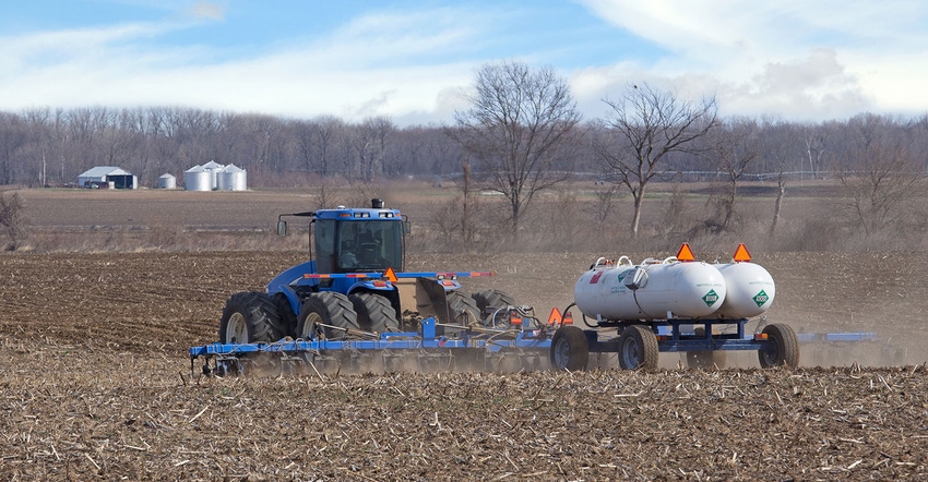 Farm tractor pulling anhydrous ammonia tanks fertilizing farmland