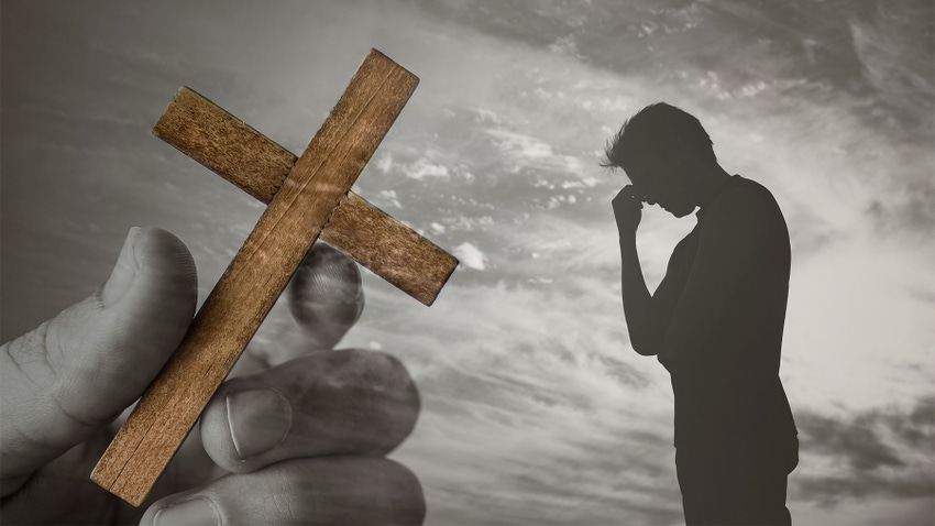 A composite photo of a hand holding a wooden cross and a silhouette of a young man appearing sad
