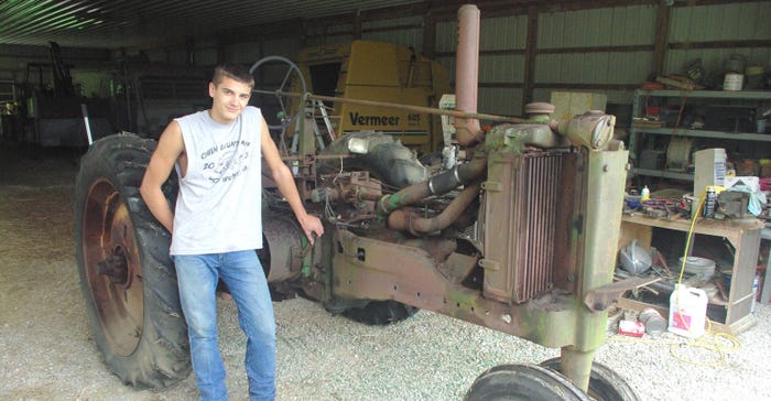 Corbin Forston with John Deere A tractor before he restored it