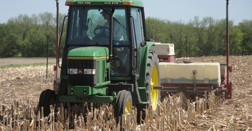 tractor planting soybeans down old corn residue rows