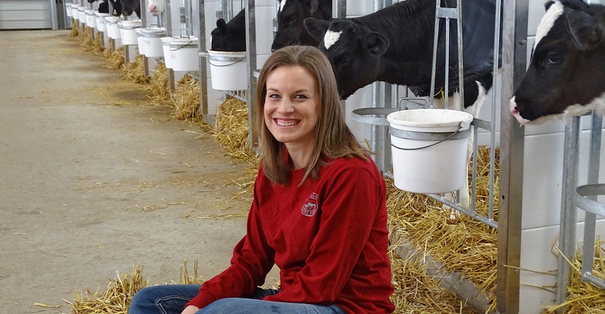 Andrea Brossard seated in Holstein dairy barn