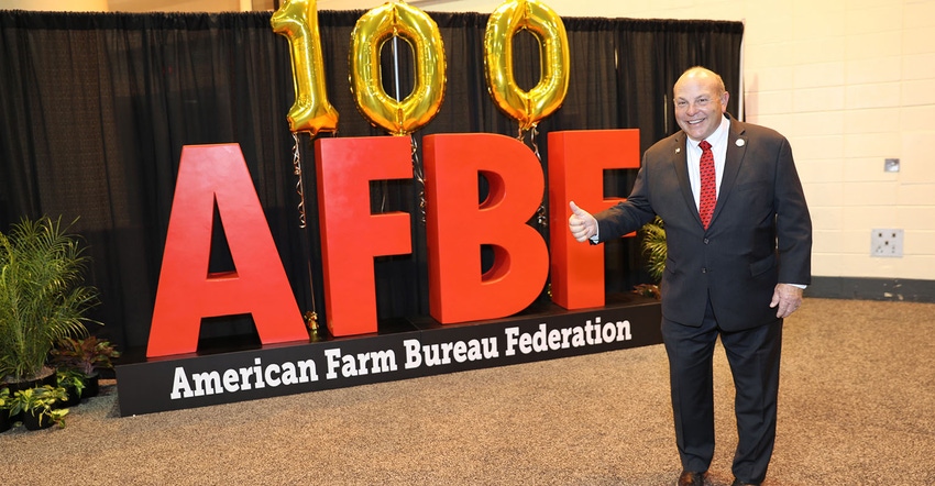 Zippy Duvall standing by banner or balloons celebrating 100th annual convention of AFBF